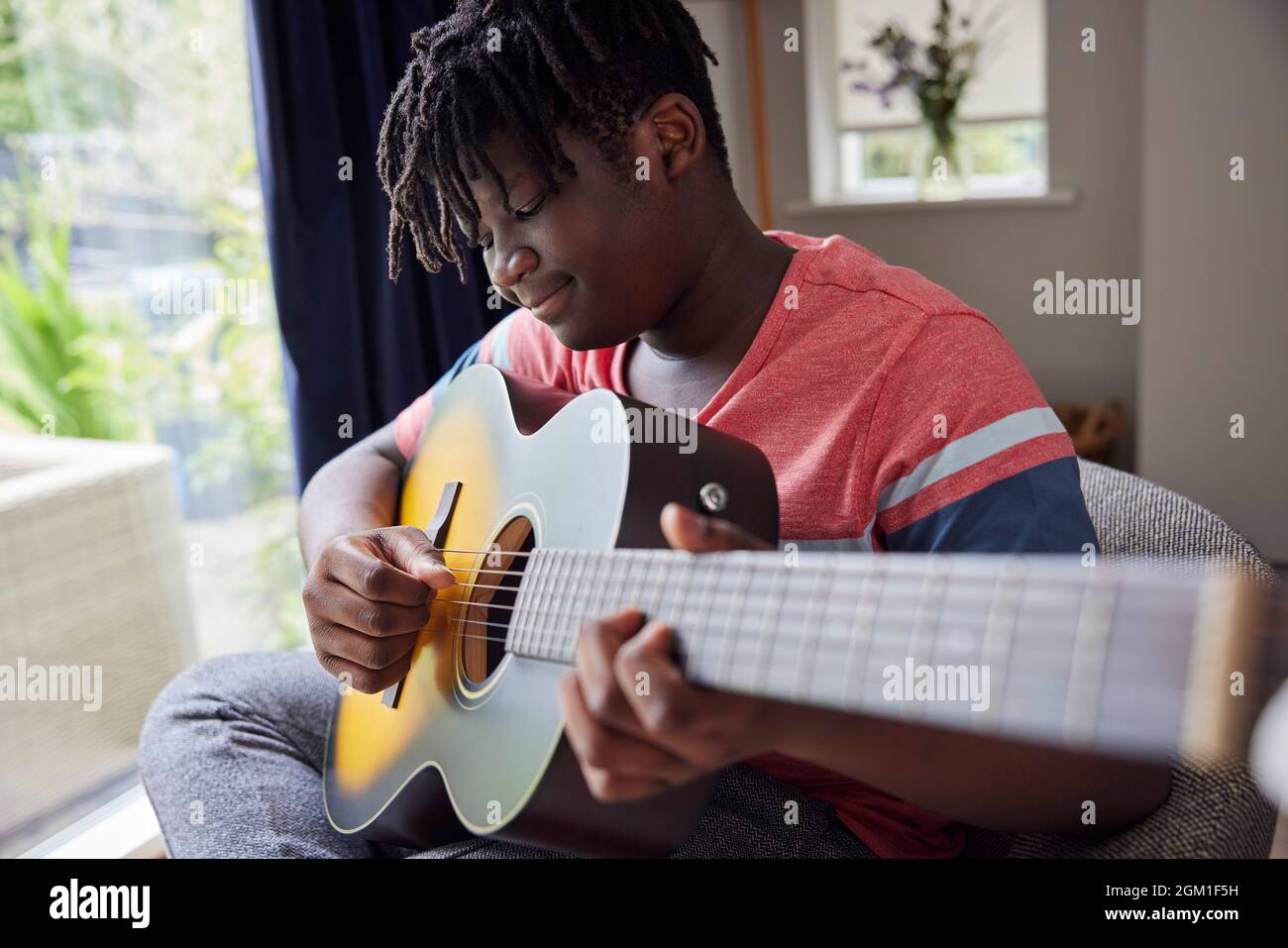 Teenage Boy apprendre à jouer de la guitare acosutique à la maison Banque D'Images