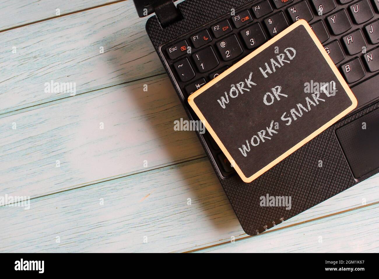 Concept d'entreprise. Mini tableau noir avec texte TRAVAILLER DUR OU TRAVAILLER INTELLIGEMMENT? sur ordinateur portable. Banque D'Images