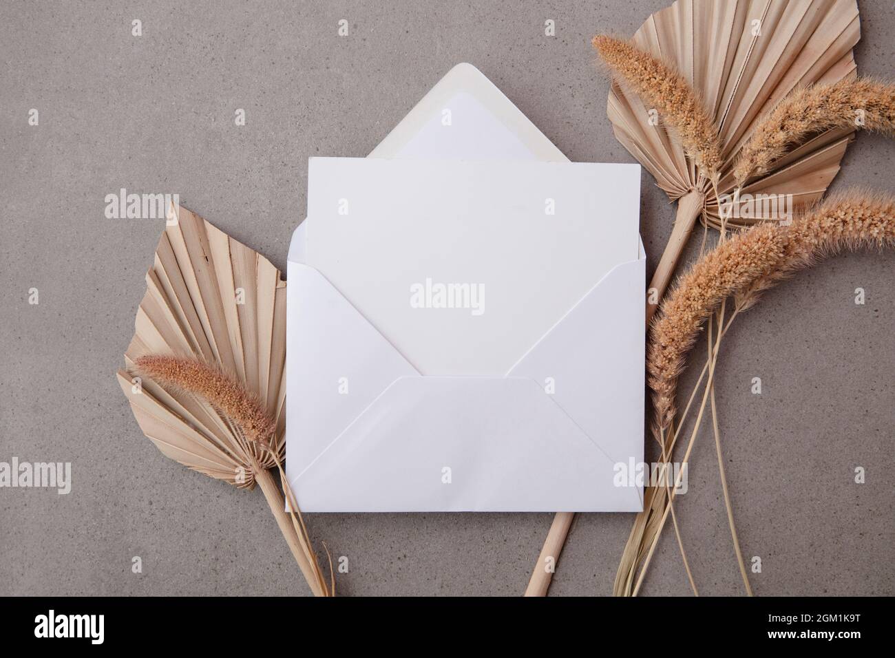Carte d'invitation vierge bohémien entourée de feuilles de palmier séchées naturelles et de graminées. Mariage et célébration Banque D'Images