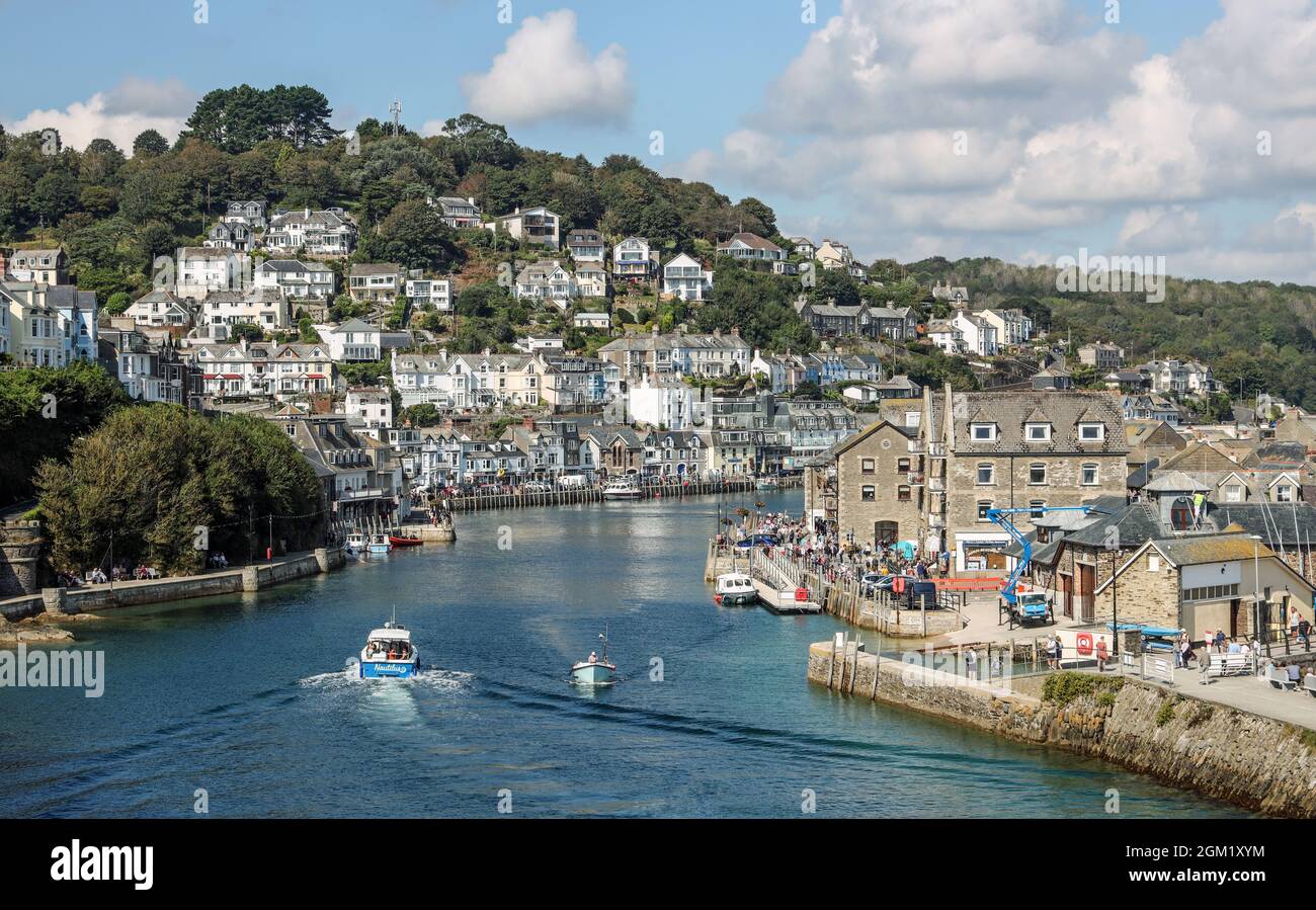 Baigné par le soleil de septembre, la foule se délectait des cafés et des boutiques au bord de la rivière Looe, certains attendant une promenade en bateau. Le Cornouailles Banque D'Images