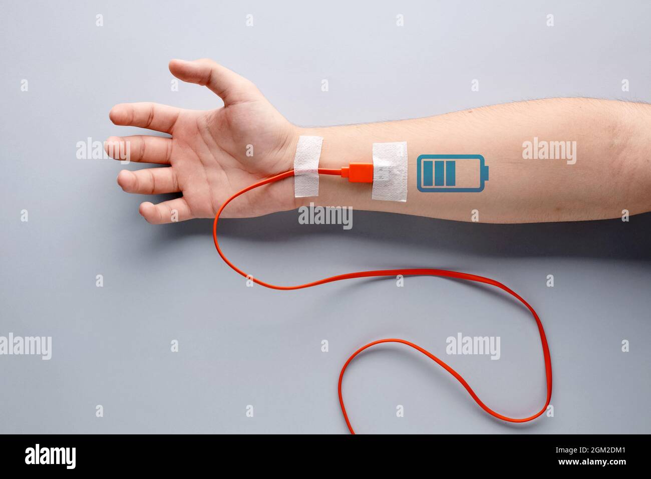 Câble de chargement USB branché sur un bras mâle avec symbole de chargement de la batterie. Fatigue, recharge, vitalité, endurance, surtâches, endurance, fatigue ou vie Banque D'Images