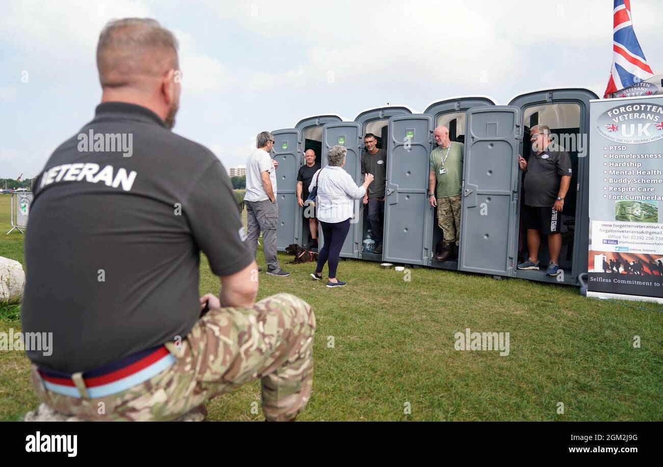 Les anciens combattants Ian Baillie, Mike Hewlett et son chien Buster, Gary Sprakes et Chris Nicholls, discuter avec les membres du public pendant qu'ils passent 120 heures dans des cabines de toilette portatives sur Southsea Common à Portsmouth, Hampshire, pour recueillir de l'argent pour les anciens combattants oubliés du Royaume-Uni qui soutiennent les anciens membres des forces armées. Les anciens combattants de l'Armée et du Service sous-marin de la Royal Navy, qui visent à amasser 1,500 GBP, ont commencé leur sit-in mercredi et se termineront à 16h le dimanche. Date de la photo : jeudi 16 septembre 2021. Banque D'Images