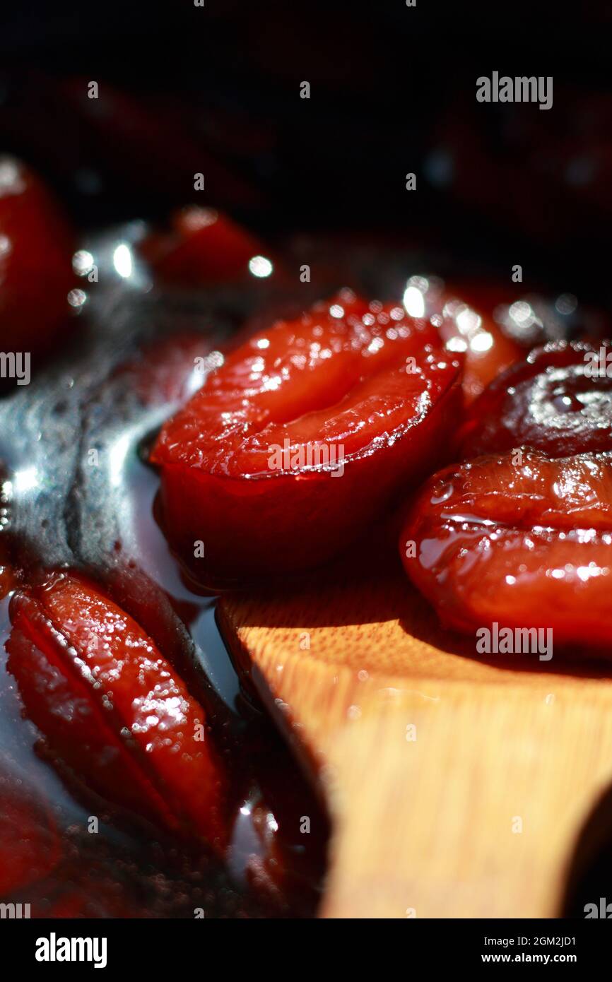 La confiture de prunes est cuite et remuée avec une cuillère en bois. Faible profondeur de champ Banque D'Images