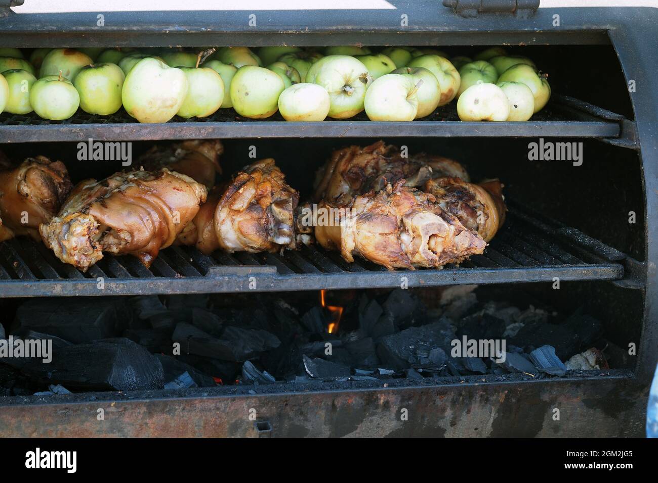Griller des aliments. La viande est cuite au barbecue avec des coals. Porte-jarret de porc avec pommes sur le barbecue. Photo de haute qualité Banque D'Images