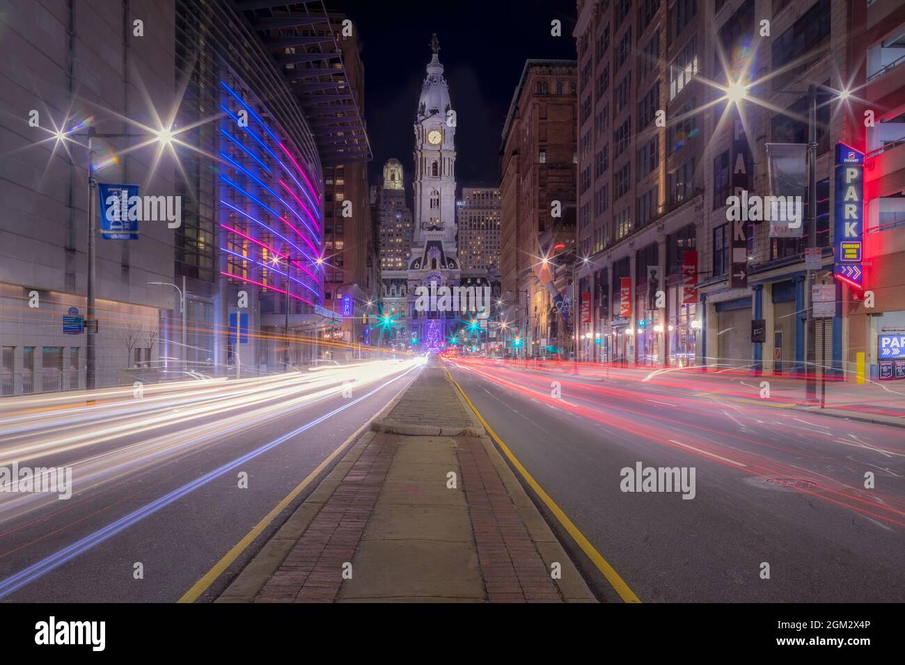Quartier des affaires de Philadelphie - vue sur l'hôtel de ville éclairé pendant le crépuscule. La longue exposition a créé des traînées de lumière des véhicules qui passent et Banque D'Images
