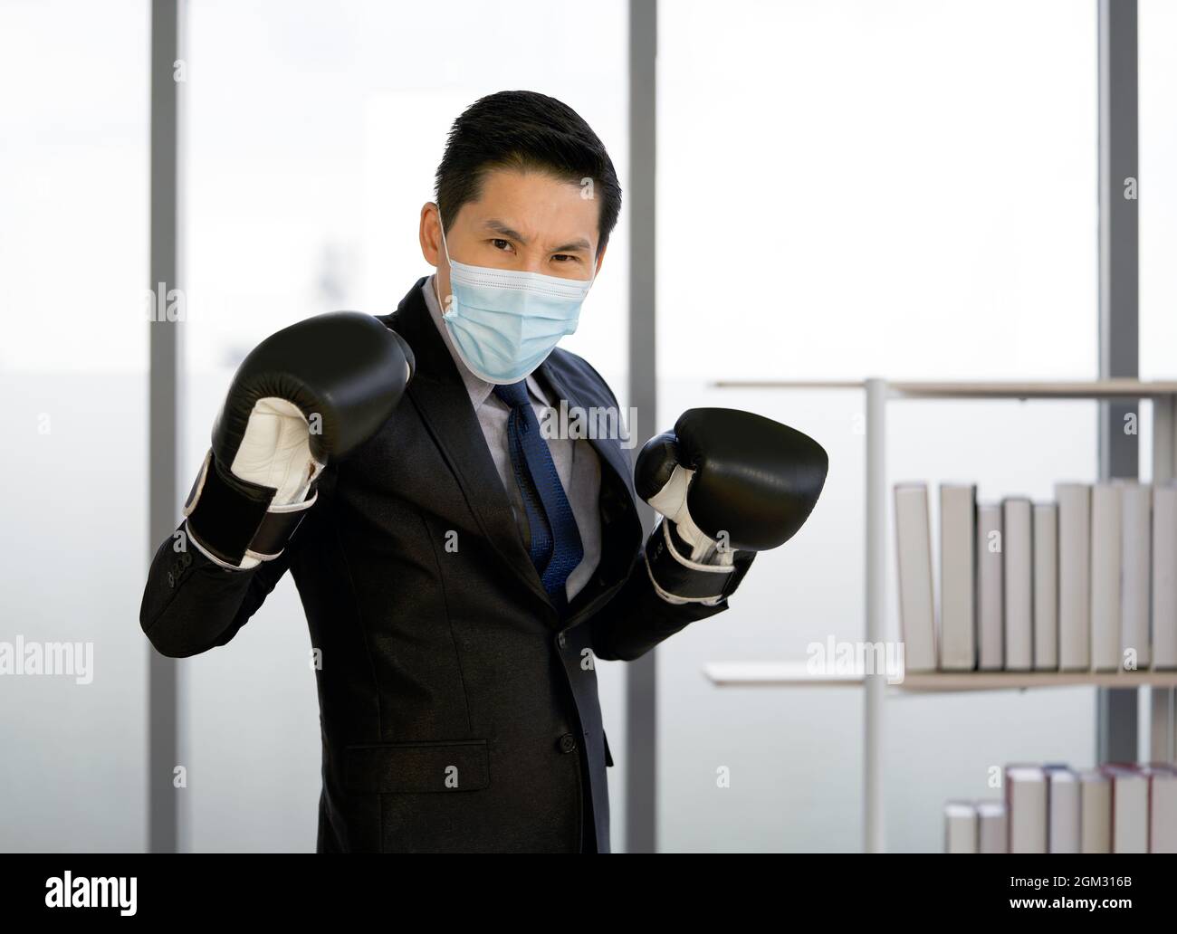 Homme d'affaires asiatique habillé en costume et cravate, portant un masque  et un gant de boxe. Posture debout prête pour la boxe. Le concept de ne pas  vous laisser Photo Stock -