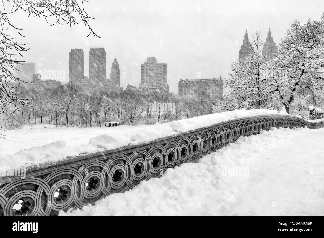 Bow Bridge à Central Park, les San Remo Towers et d'autres gratte-ciel qui composent l'horizon du centre de Manhattan pendant une tempête de neige. Banque D'Images