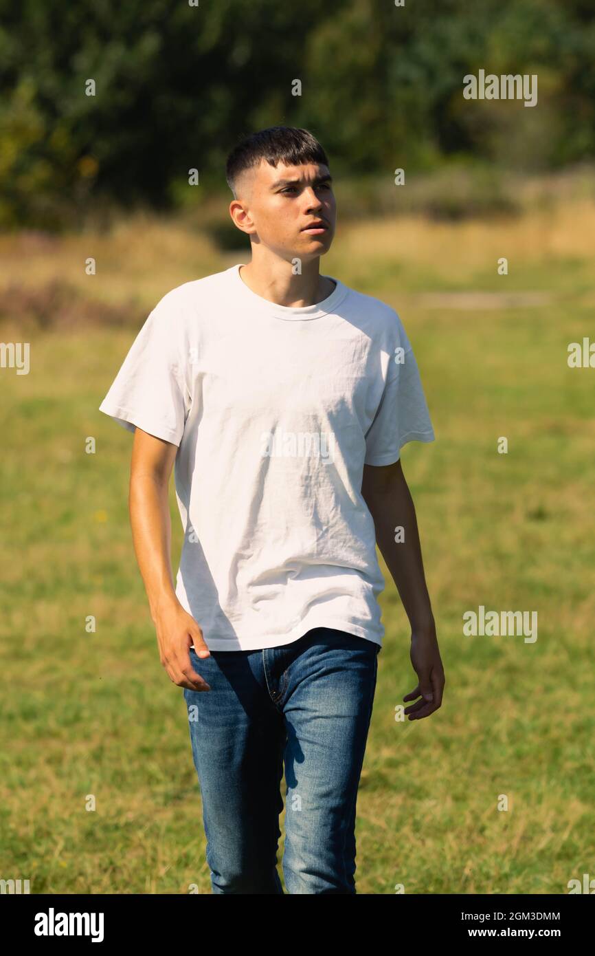 jeune garçon de 18 ans dans un t-shirt blanc à l'extérieur et jeans en denim bleu Banque D'Images