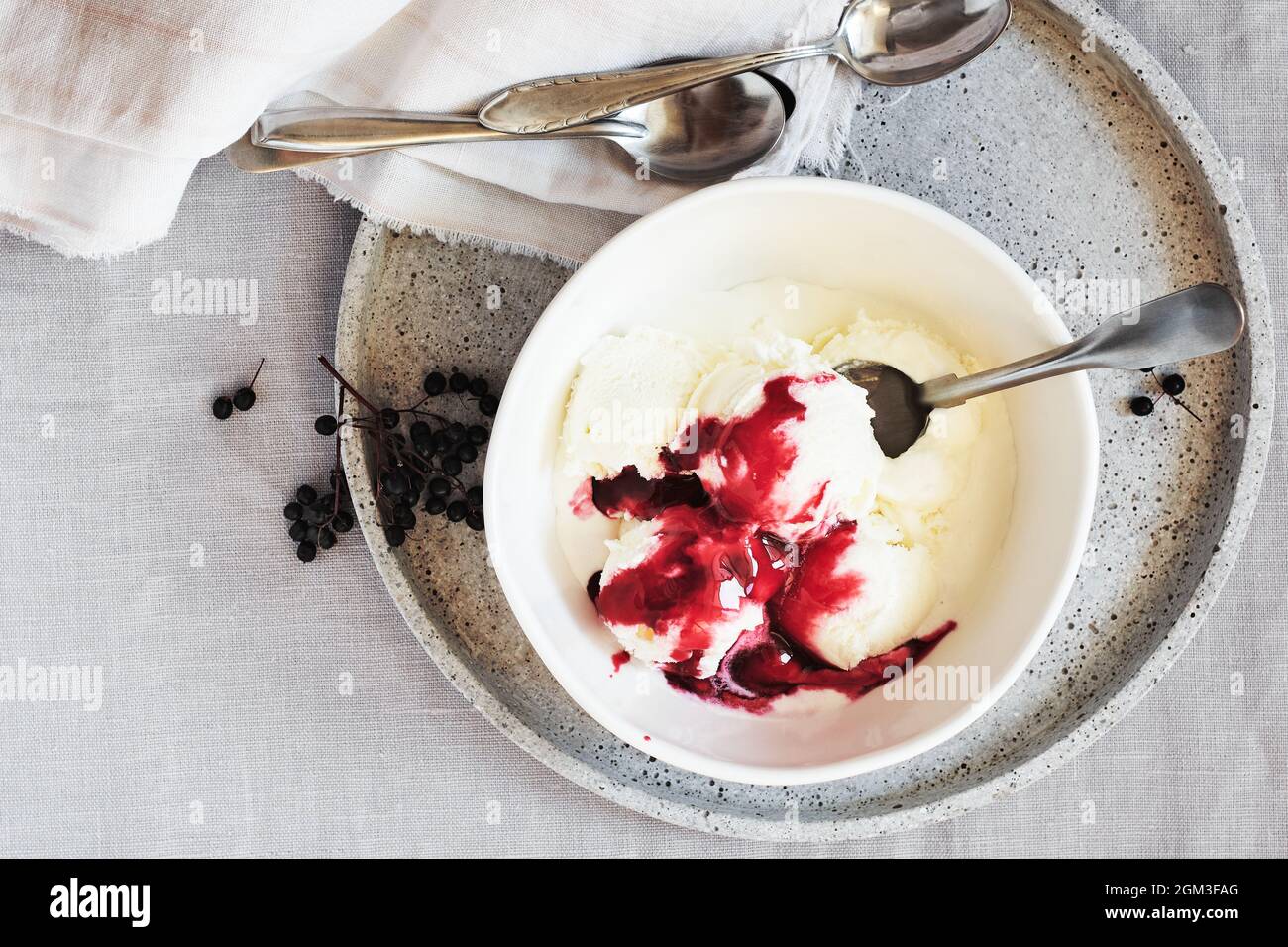 Glace à la vanille et sauce aux baies de sureau dans un bol sur une nappe en lin, vue du dessus. Banque D'Images