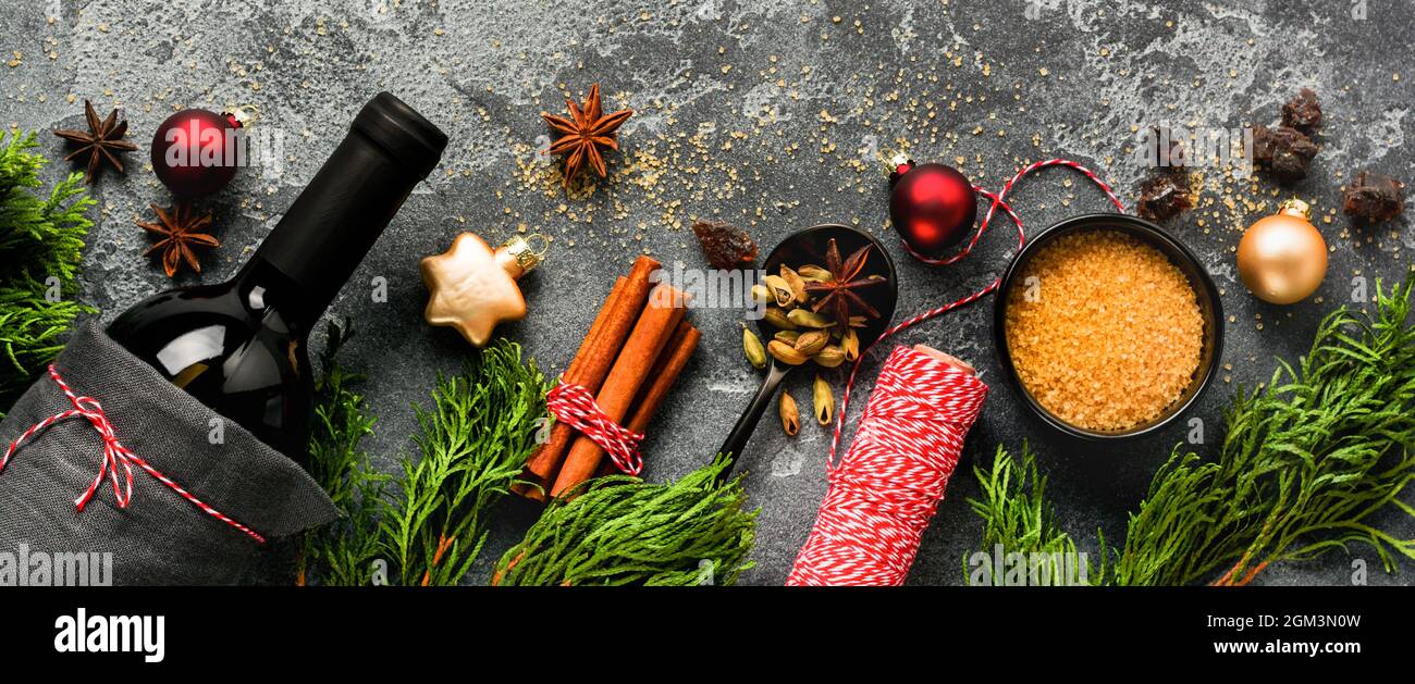 Boisson chaude au vin chaud avec agrumes, pomme, grenade et épices dans une casserole en aluminium avec jouets d'arbre de Noël vintage et branche de sapin sur bac en béton Banque D'Images