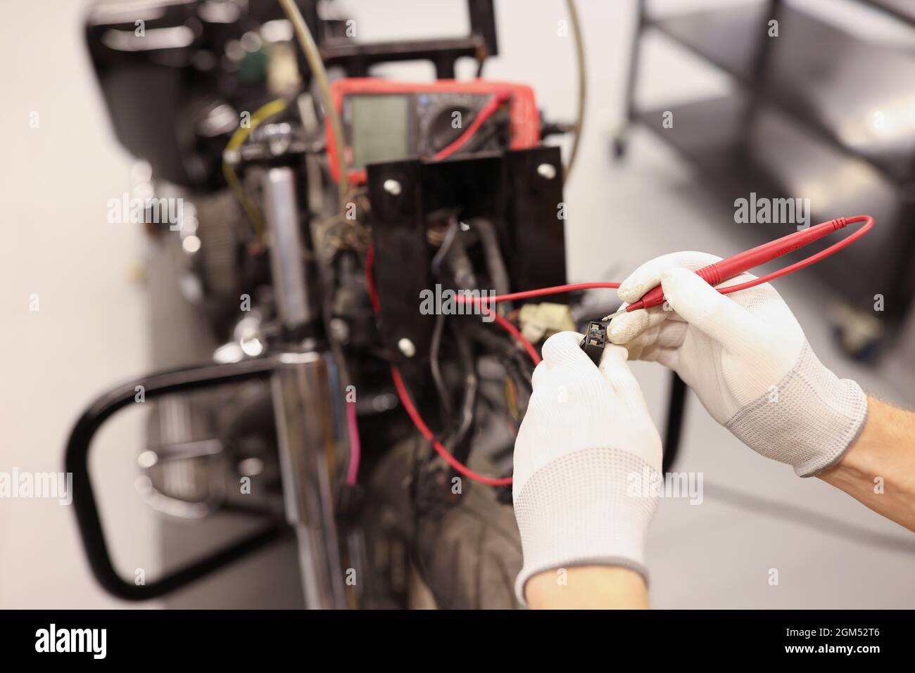 Un réparateur mâle vérifie les circuits électriques de la moto à l'aide d'un testeur de proximité Banque D'Images