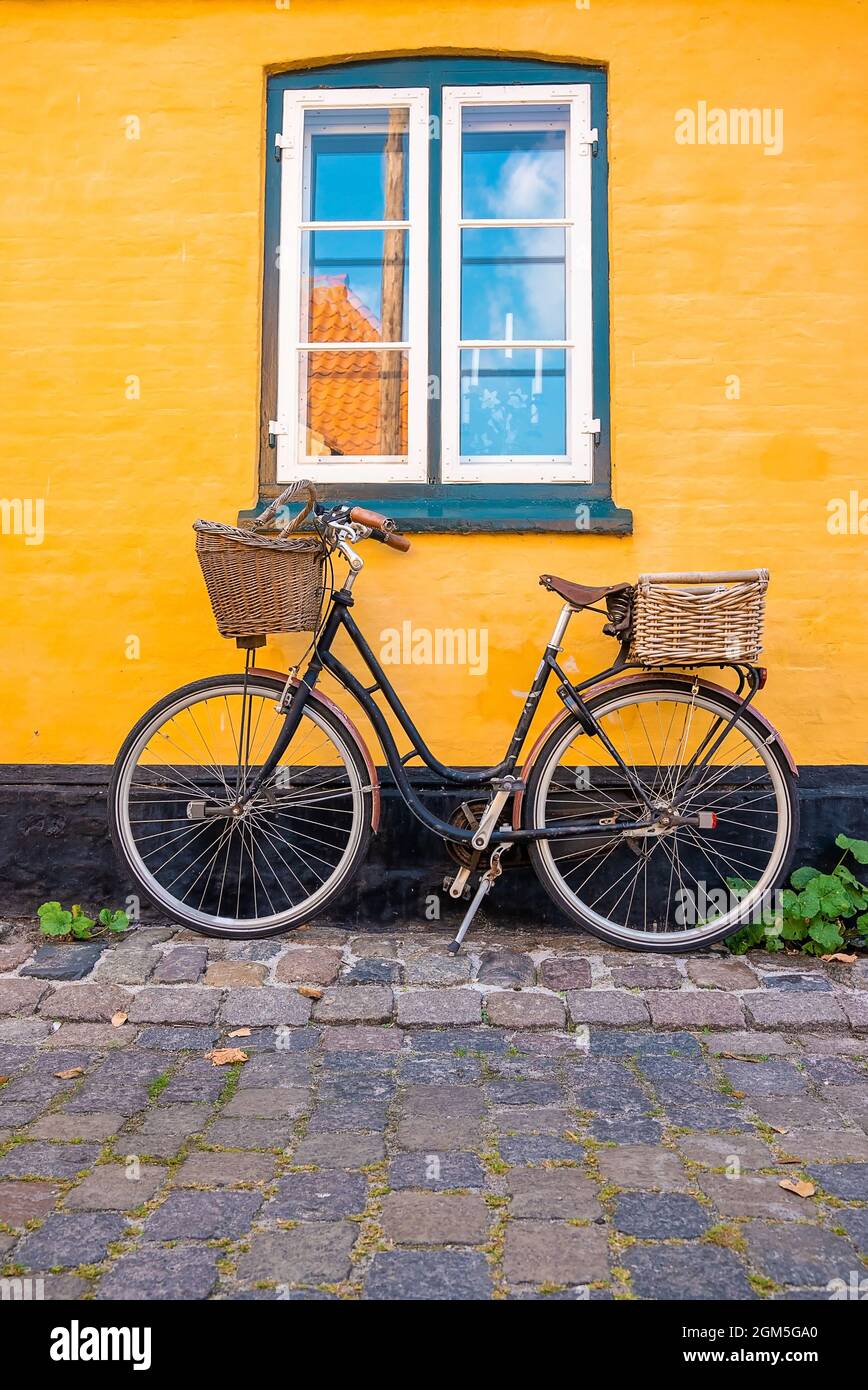 Vélo stationné près du mur jaune d'une vieille maison Banque D'Images