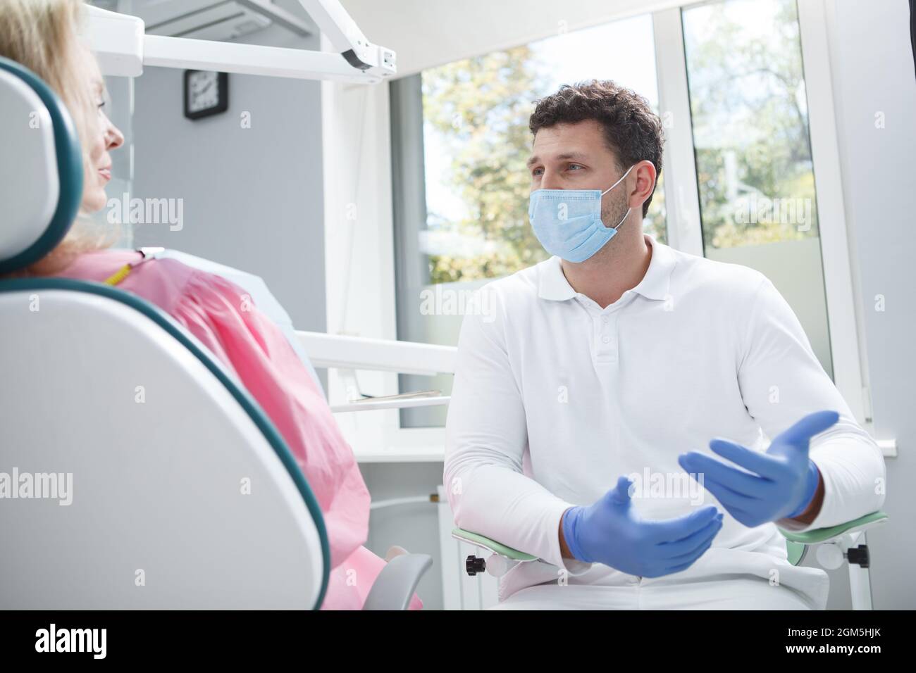 Dentiste professionnel portant un masque médical, parlant à son patient Banque D'Images