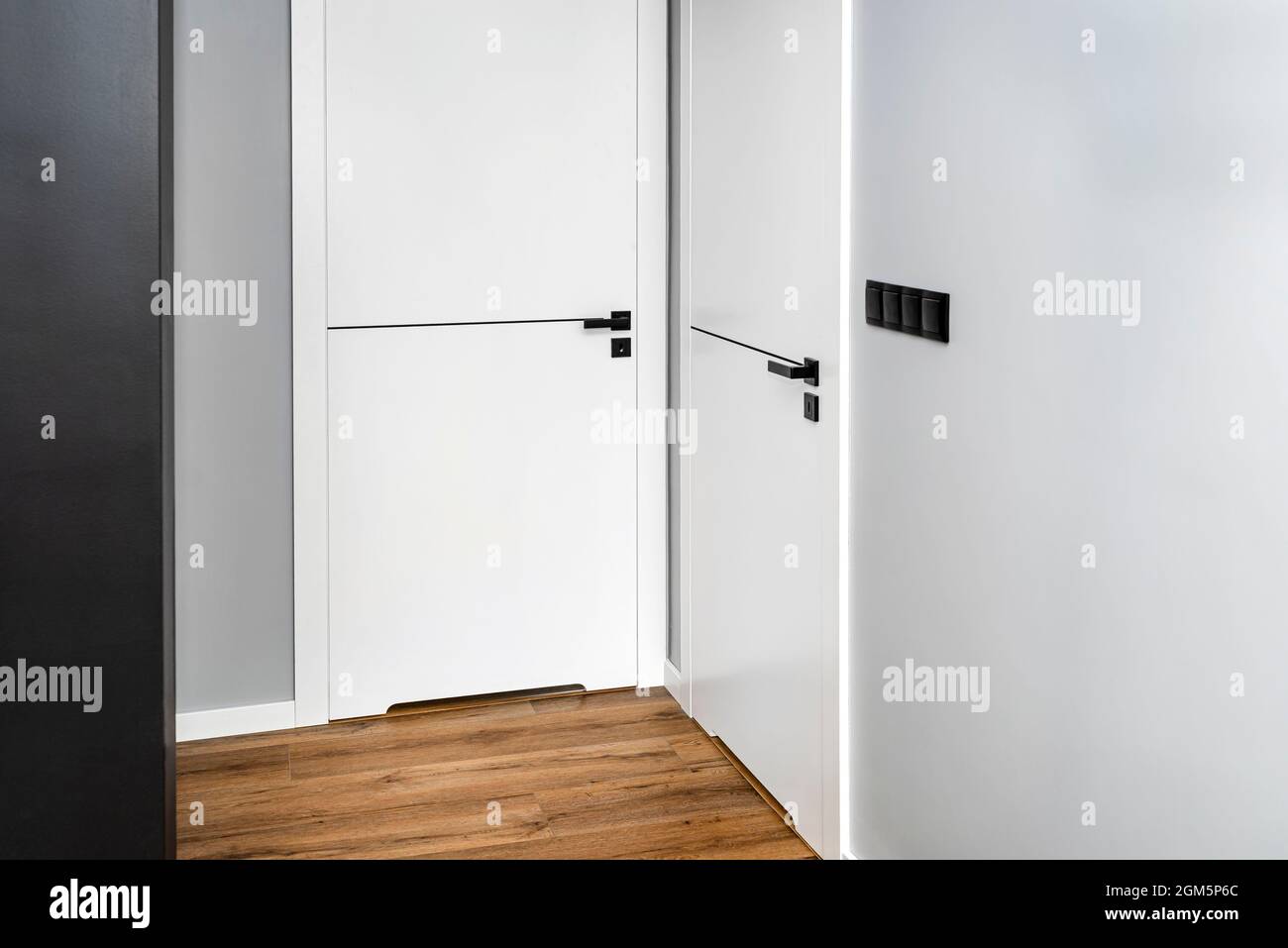 Une porte blanche avec un dégagement de ventilation avec une poignée noire  mate et une ligne noire au milieu dans une maison moderne avec des panneaux  en vinyle sur le plancher Photo