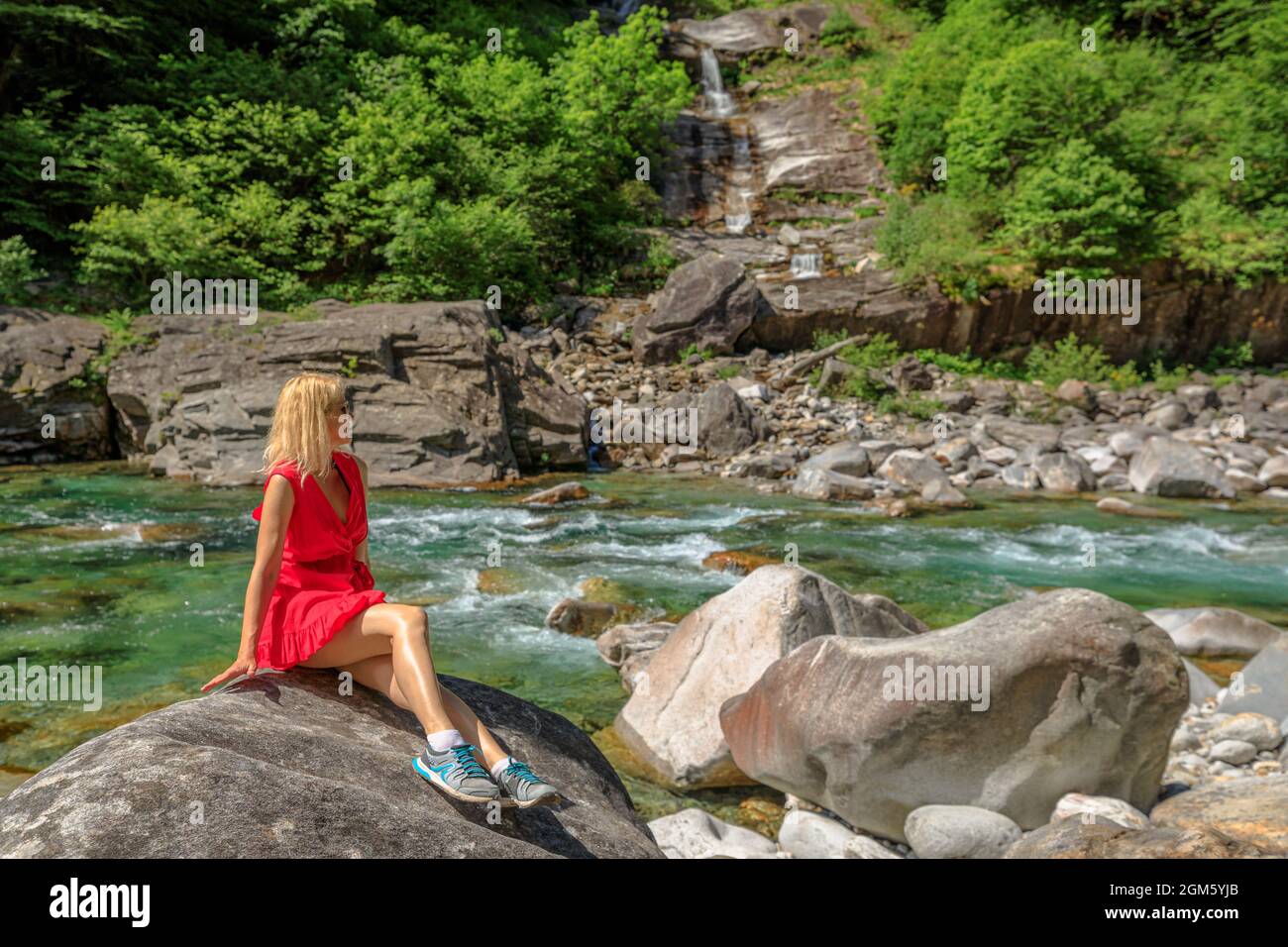 Femme assise sur les rochers de la rivière Verzasca. Vallée de Verzasca par la ville de Lavertèzzo. Célèbre point de repère pour les loisirs au bord de la rivière et la haute plongée au Tessin Banque D'Images