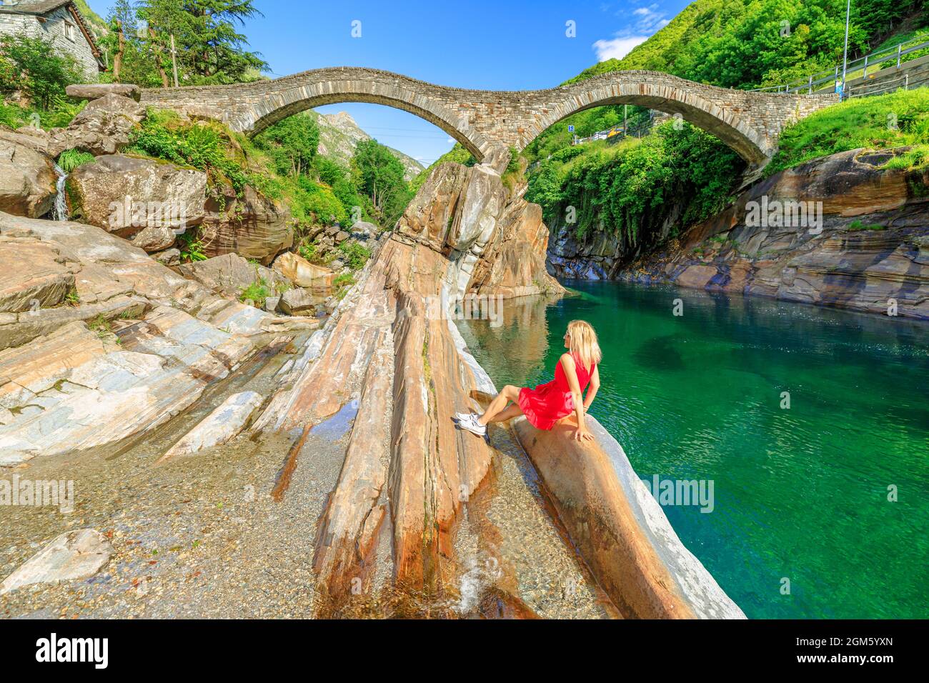 Femme de détente assise par le vieux pont romain en pierre: Ponte dei Salti sur la rivière Verzasca. Vallée de Verzasca par la ville de Lavertèzzo. Célèbre monument pour Banque D'Images