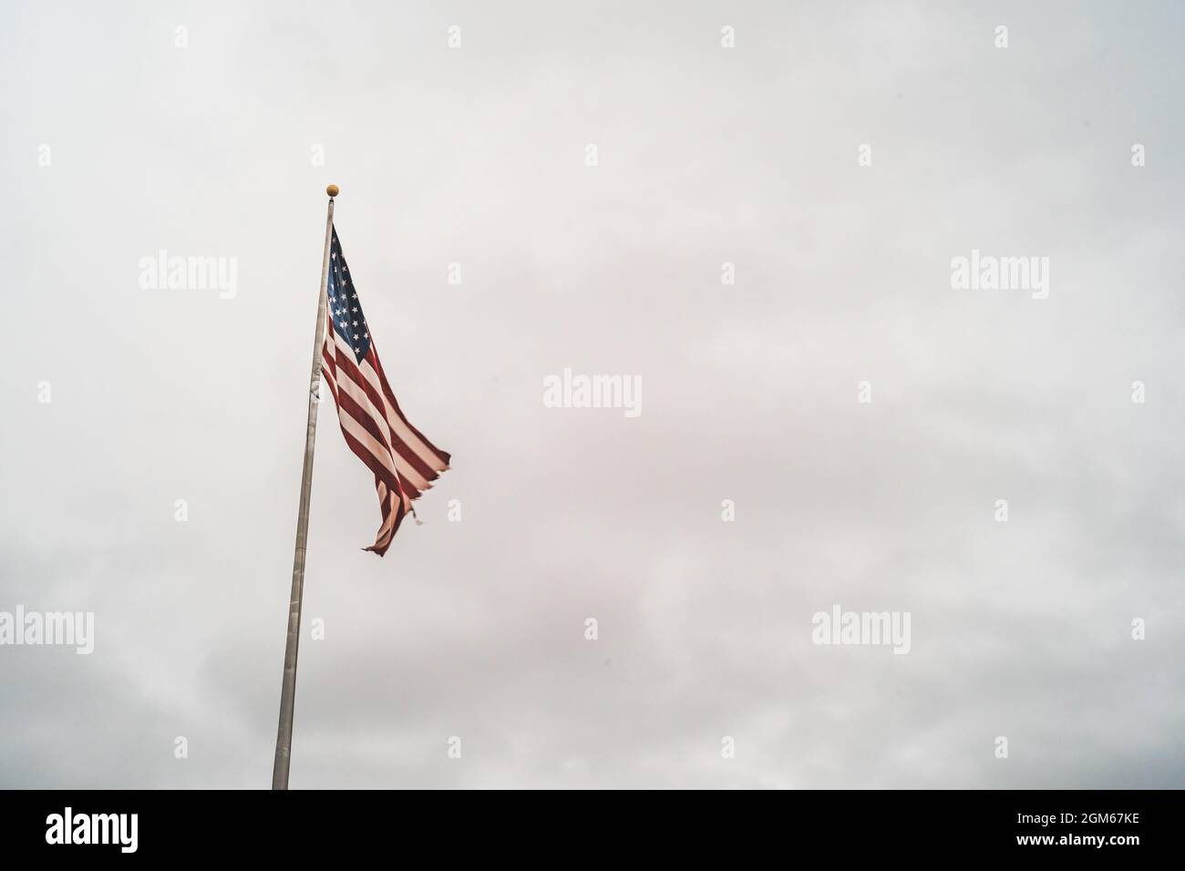 Drapeau américain agitant contre un ciel sombre couvert Banque D'Images