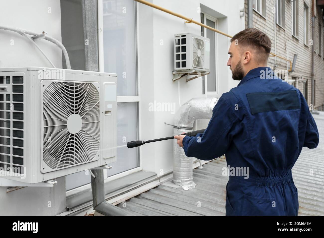 Technicien mâle climatiseur nettoyage extérieur Photo Stock - Alamy