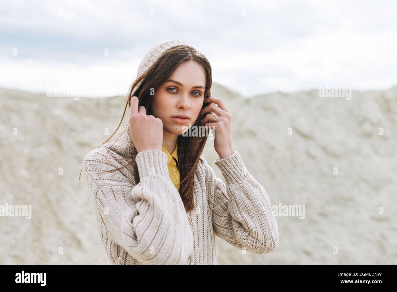 Portrait de beauté de mode de jeune femme avec de longs cheveux en tricoté gilet sur fond de désert, tenue d'automne Banque D'Images