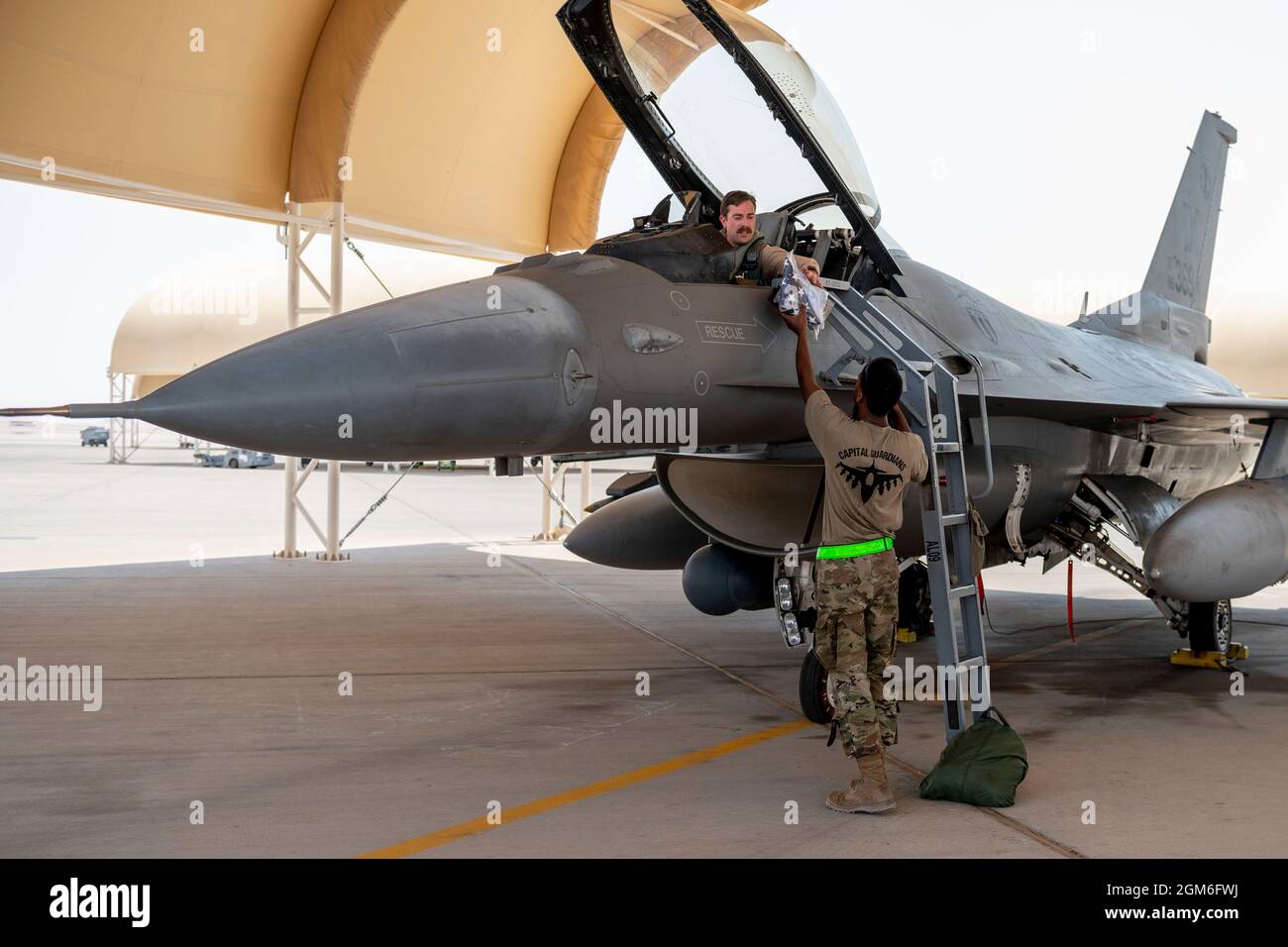 Un chef d'équipage de l'armée de l'air des États-Unis, au 121e Escadron de génération de chasseurs expéditionnaires, remet un drapeau des États-Unis à bord d'un faucon de combat F-16 pour piloter avec le 121e Escadron de chasseurs expéditionnaires à la base aérienne de Prince Sultan, Royaume d'Arabie saoudite, le 27 août 2021. En plus du soutien logistique et de la main-d’œuvre, la 378e Escadre expéditionnaire aérienne a fourni une force aérienne de combat pour assurer la supériorité aérienne du Commandement central des États-Unis pendant les opérations d’évacuation non combattantes en Afghanistan. (É.-U. Photo de la Force aérienne par le sergent d'état-major. Caleb Pavao) Banque D'Images