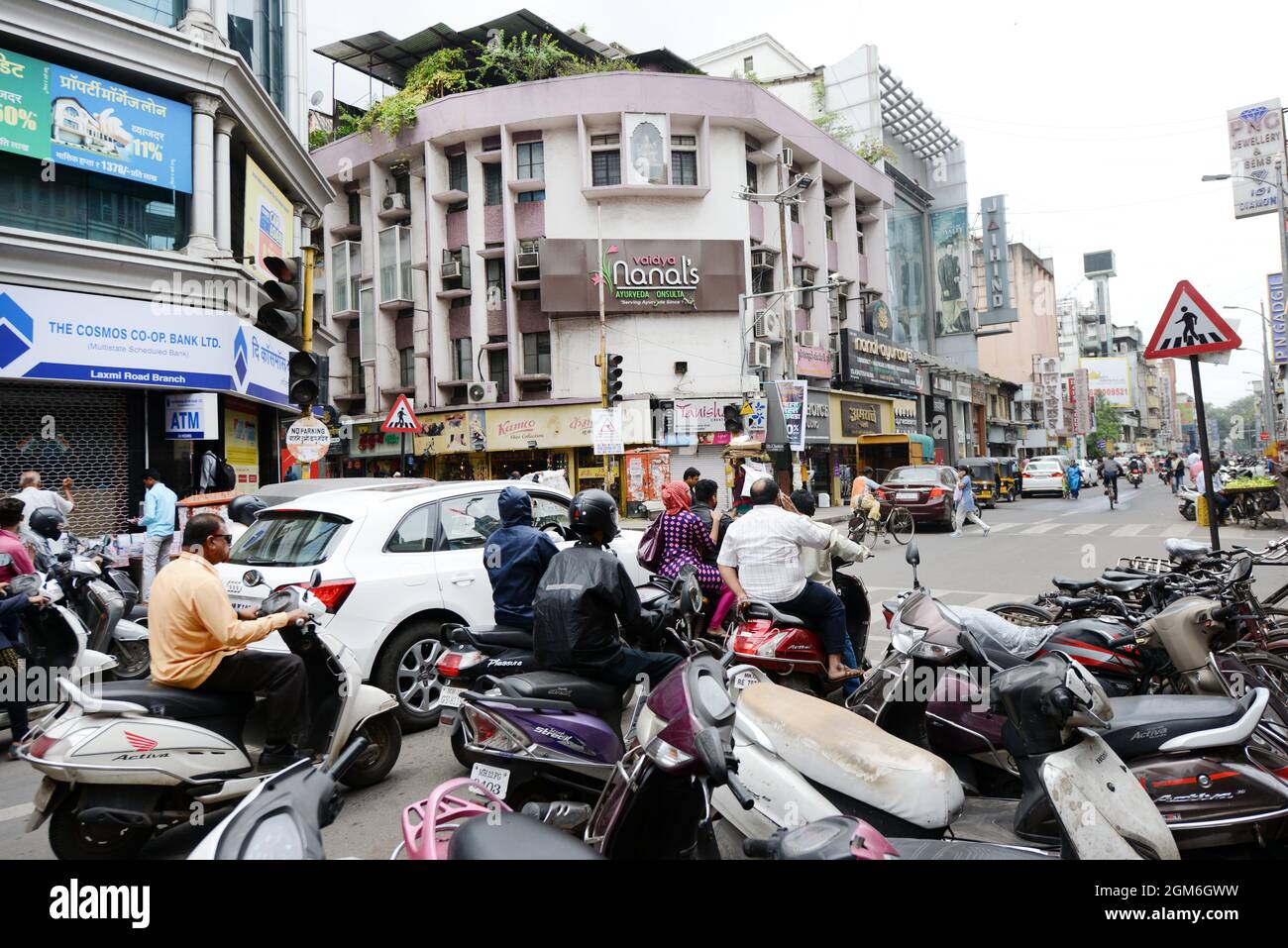Trottinettes motos et une voiture attendant un signal vert à la jonction de Sadashiv Peth et Laxmi Road à Pune, Inde. Banque D'Images