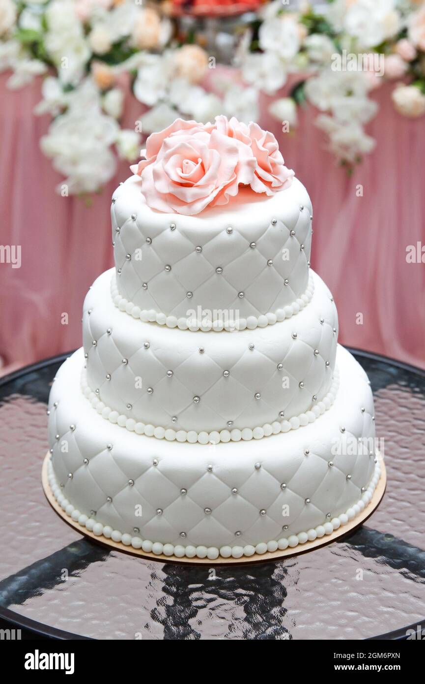 un gâteau de mariage blanc à plusieurs niveaux et des fleurs roses sur le dessus. Grand gâteau. Gâteau d'anniversaire Banque D'Images