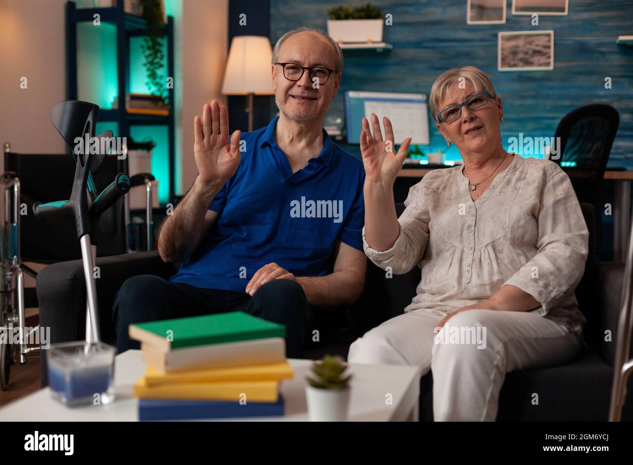 POV de couple aîné se portant la main sur la vidéoconférence dans le salon. Personnes âgées regardant la caméra tout en étant assis sur un canapé et en utilisant la communication à distance en ligne. Vieux mari et femme Banque D'Images
