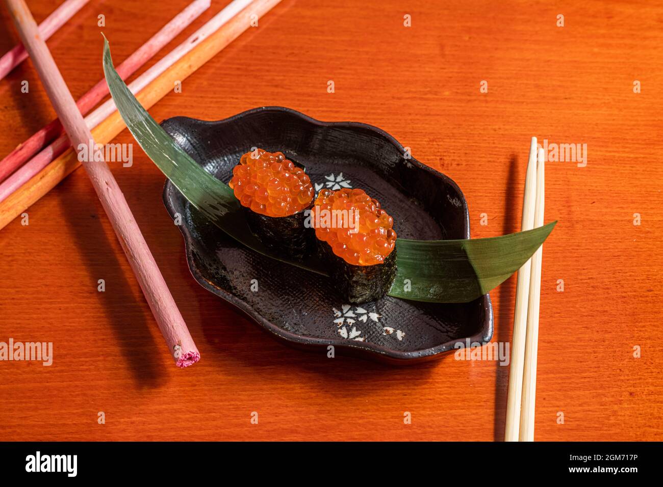 Sushi gunkan au saumon norvégien, bateau d'algues nori sur feuille de banane Banque D'Images