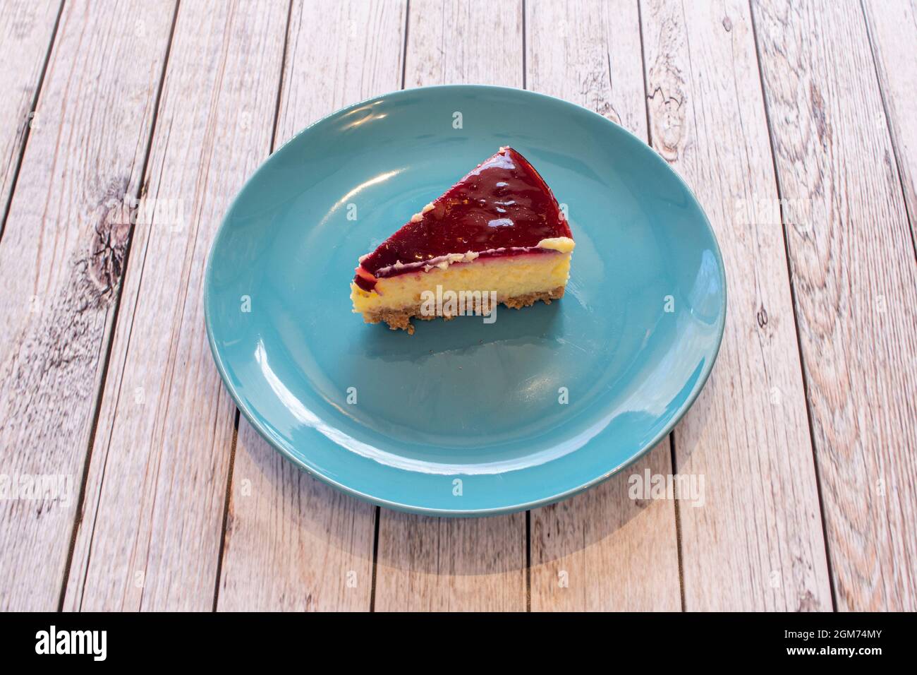 Petite portion de cheesecake fabriqué industriellement sur une assiette bleue unie Banque D'Images