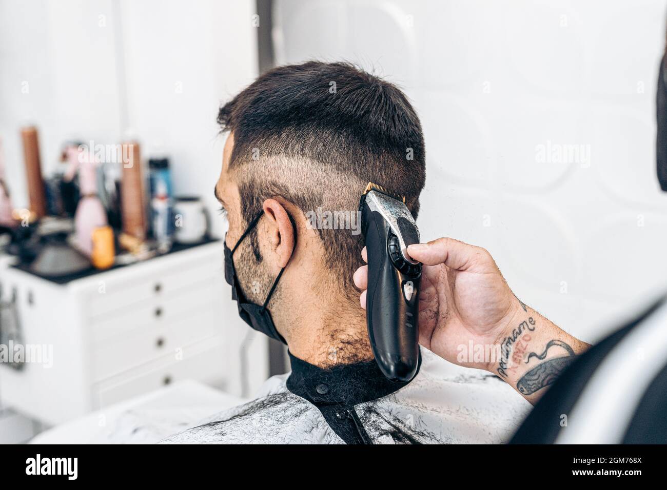 Coiffeur rasage de l'arrière de la nuque d'un homme avec un masque dans un  salon de coiffure Photo Stock - Alamy
