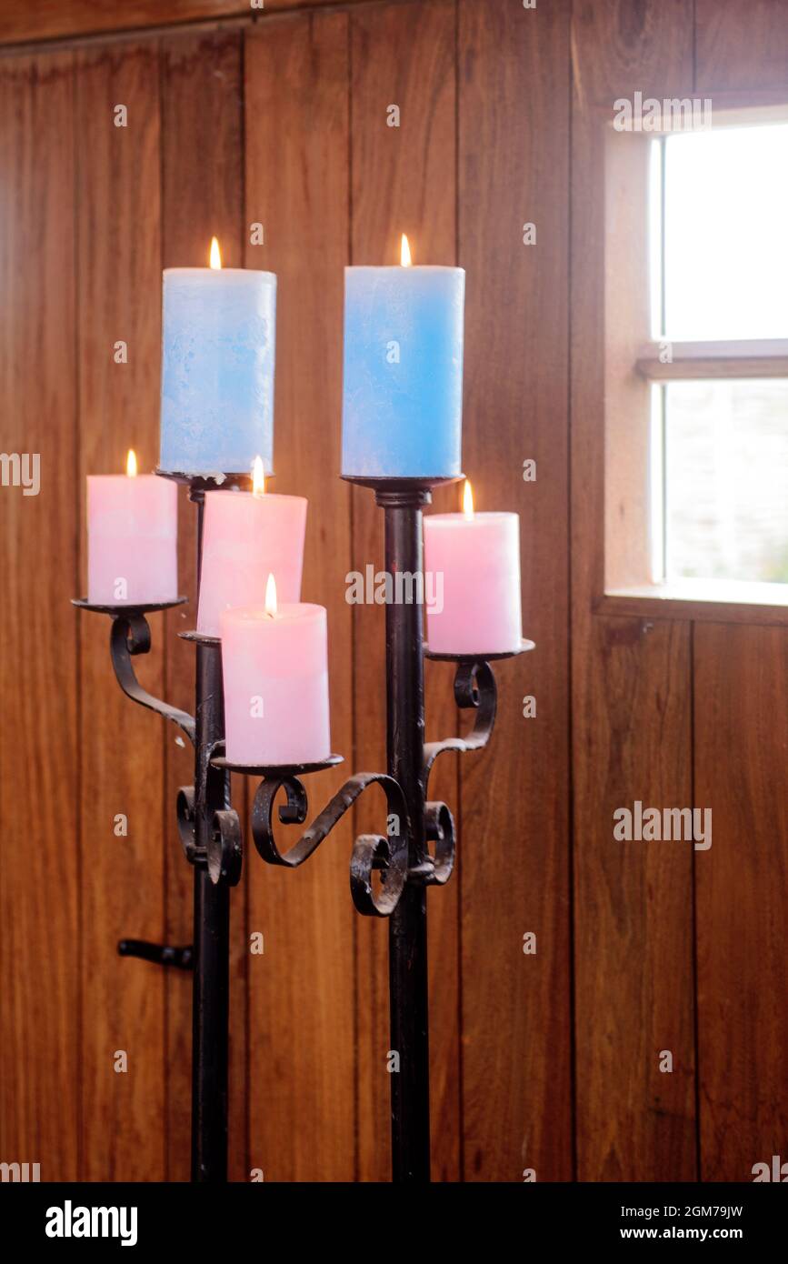 Standaard avec des bougies de couleur dans une cabine en bois avec la lumière du jour se cantant à travers les fenêtres Banque D'Images