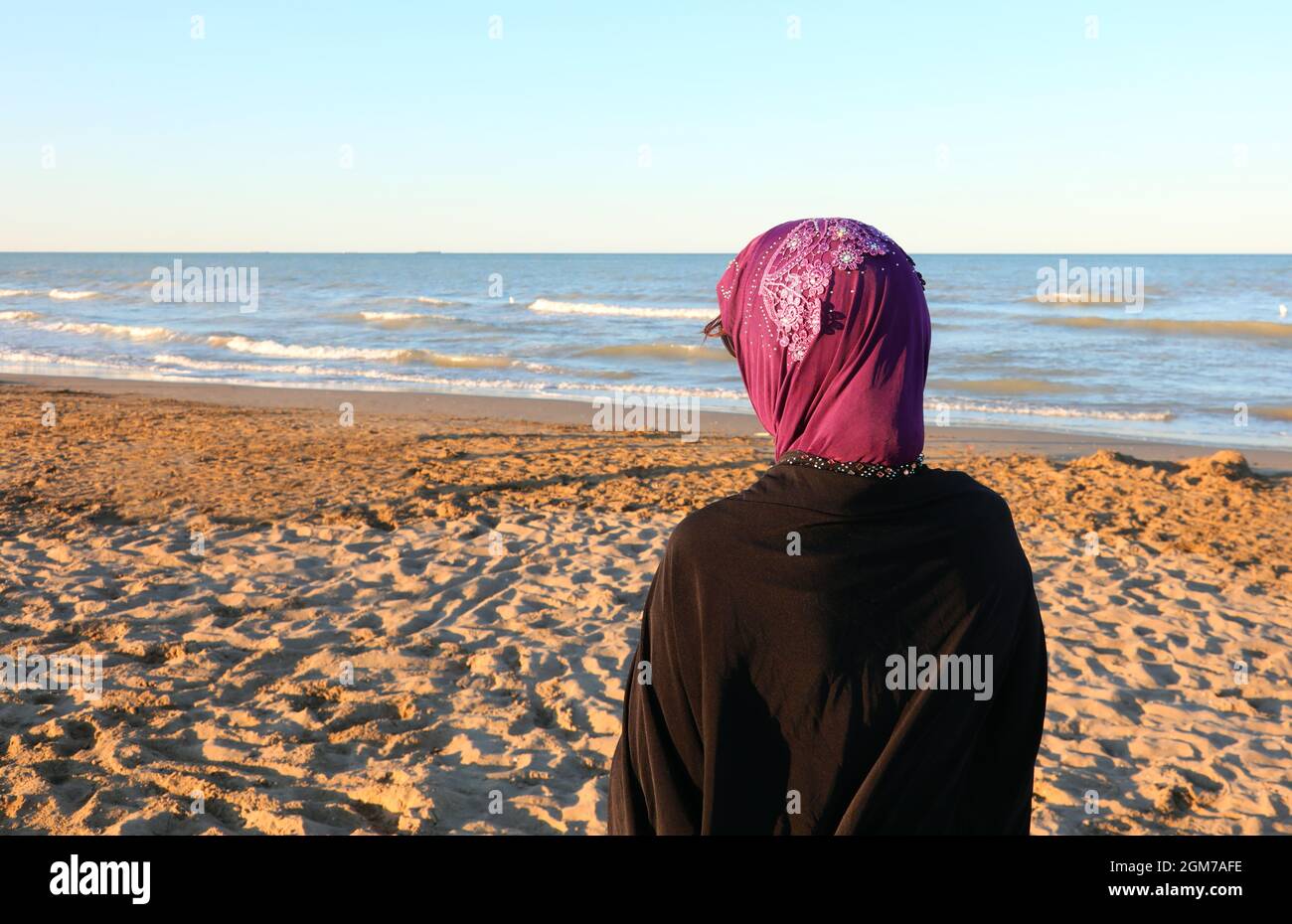 Femme arabe avec voile sur la tête attendant sur la plage au bord de la mer  Photo Stock - Alamy