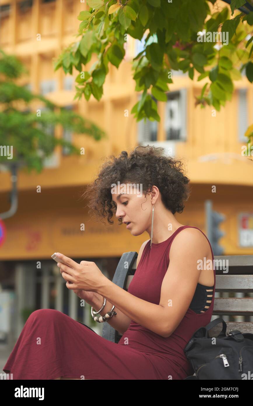 Belle jeune femme élégante qui fait des sourcils lorsqu'elle lit un message texte choquant et surprenant sur son téléphone Banque D'Images