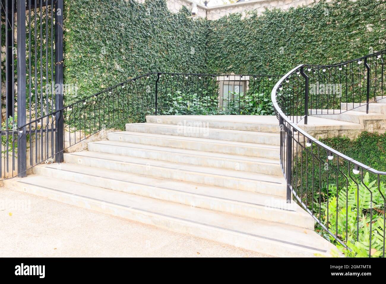 Paysage dans le jardin du parc.escalier en pierre avec rambarde de fer et herbe verte environnante, fleurs et arbres Banque D'Images