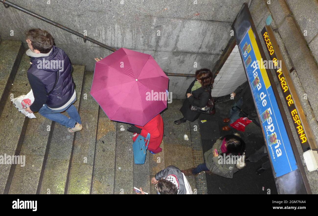 Personnes quittant la station de métro Plaza de Espana à Madrid pendant la pluie rose parapluie Banque D'Images