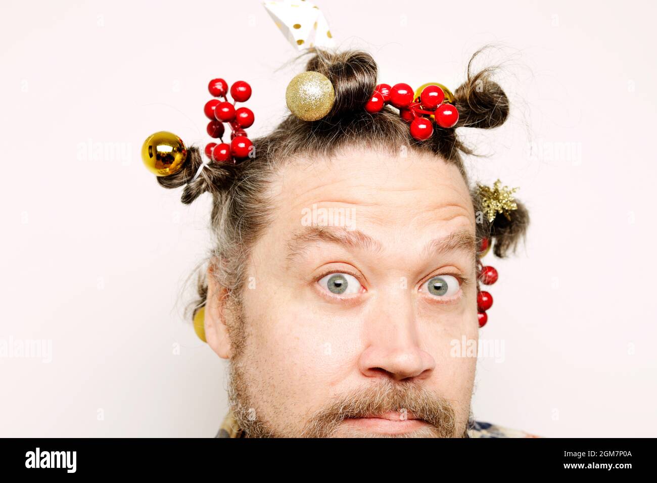 gros plan de l'homme barbu avec des yeux larges ouverts avec une expression étonnante et une coiffure drôle dans les décorations de noël Banque D'Images