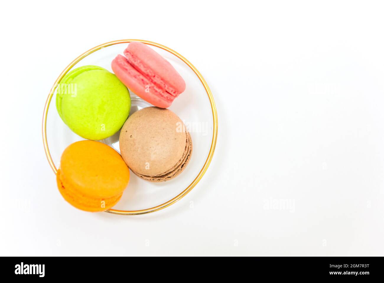 Macarons français doux et colorés ou macaron dans un bol en verre sur fond blanc, vue du dessus avec espace pour copier votre texte. Banque D'Images