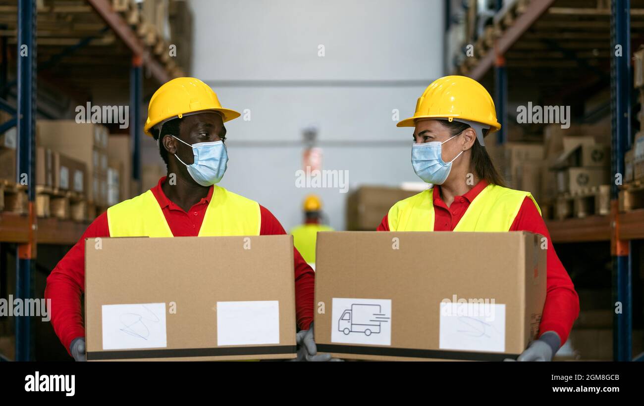 Les employés d'entrepôt chargent les boîtes de livraison tout en portant un masque facial pendant une pandémie de virus corona - concept logistique et industriel Banque D'Images