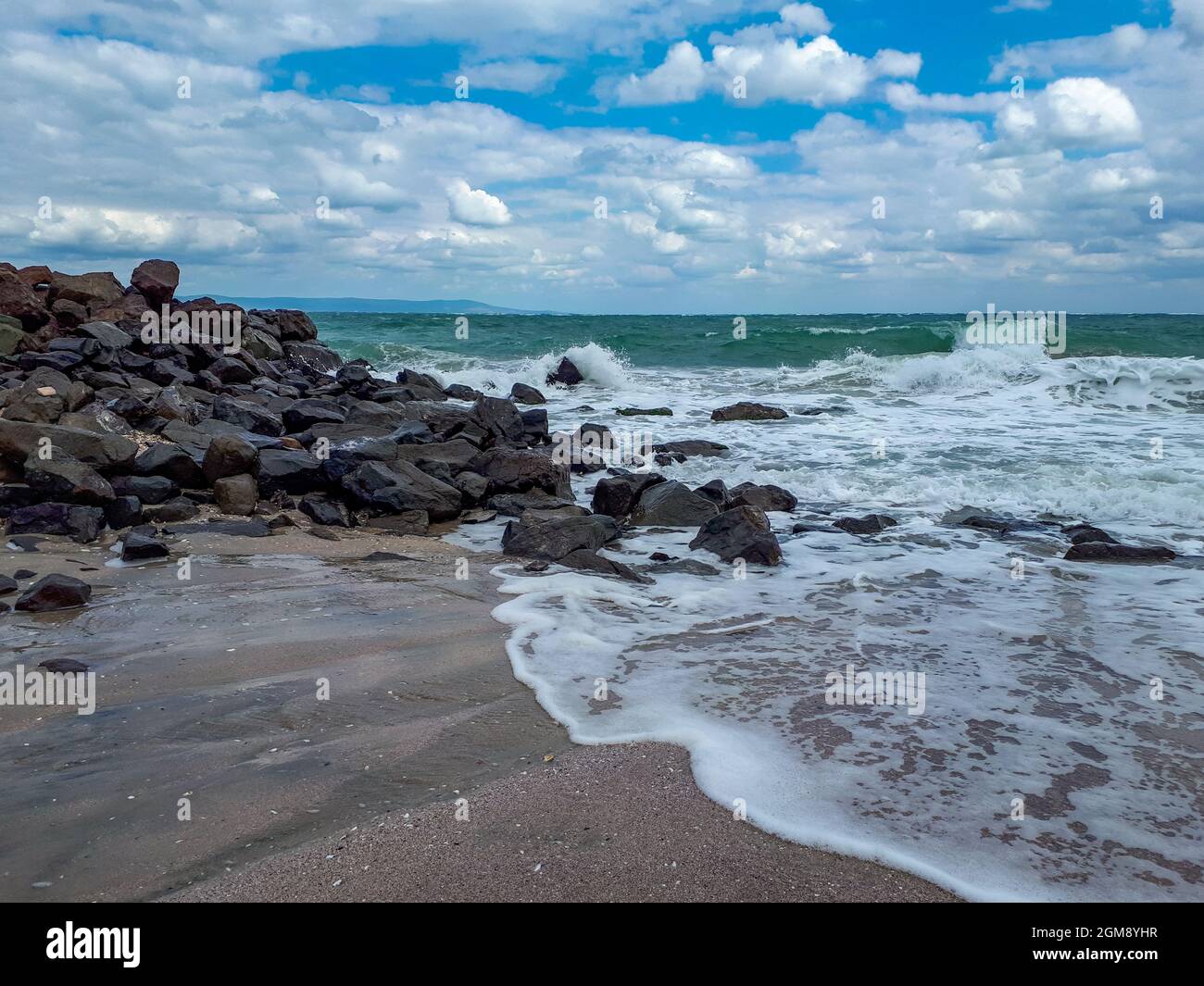 Plage de sable noir avec rochers et vagues sur la côte de la mer Noire à Pomorie, Burgas Bay, Bulgarie en été. Banque D'Images