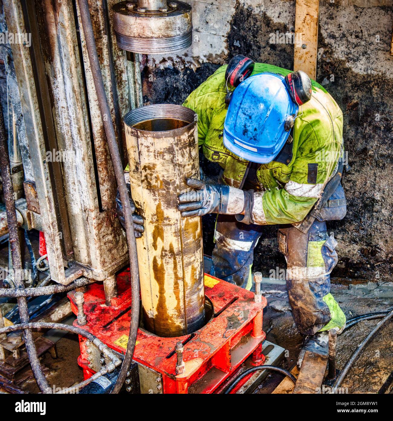 Homme forant avec un gros tube dans le sol Banque D'Images