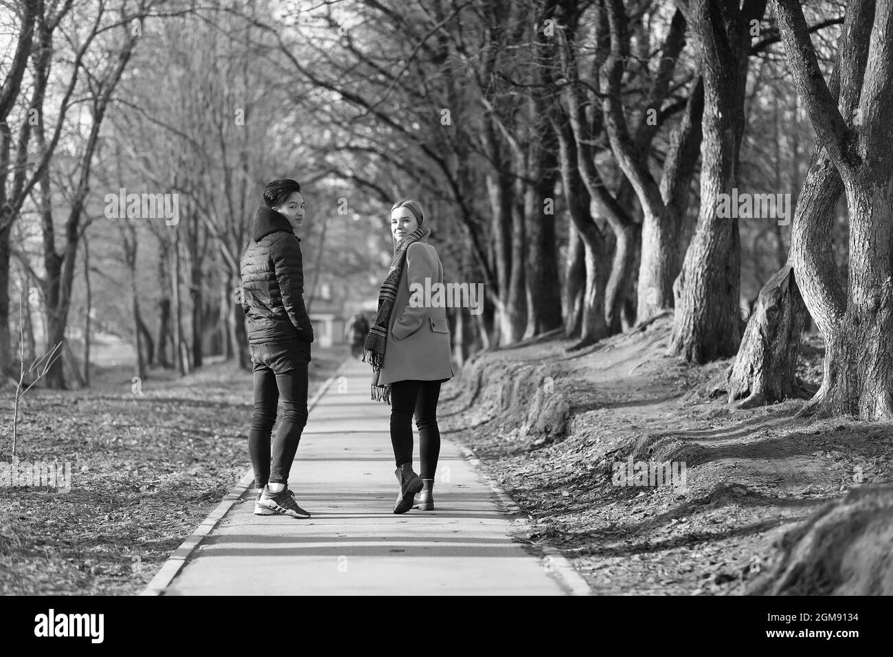 Une paire de jeunes se sont rencontrés dans le parc. Les amoureux sont assis sur un banc dans le parc de la ville. Une asiatique garçon et une fille blanche sont assis sur un banc de parc. Banque D'Images