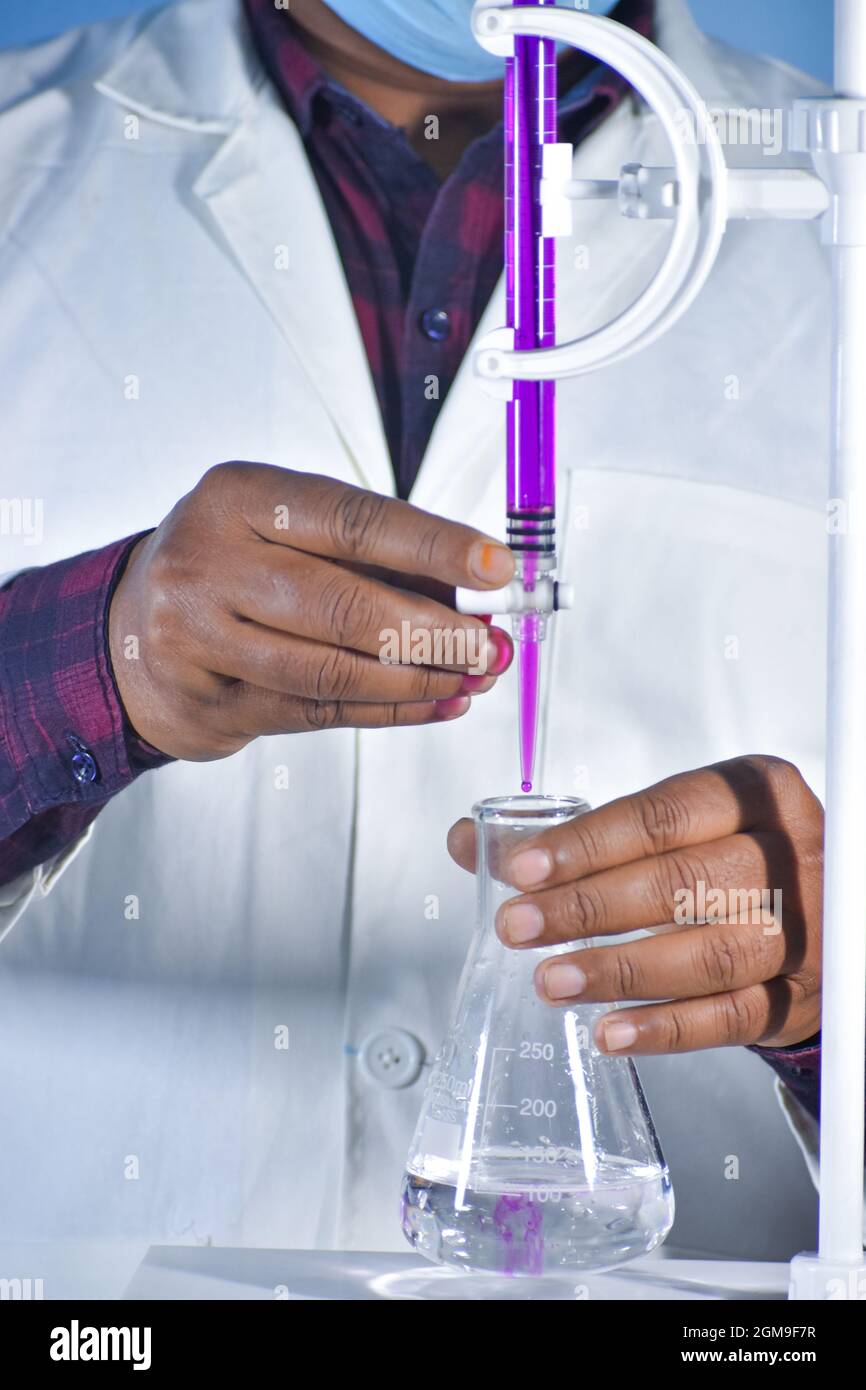 Scientifique effectuant le titrage dans un laboratoire de chimie avec la titration de Redox avec solution de couleur Banque D'Images