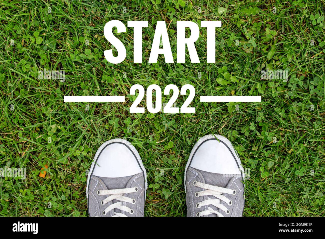 Concept de la nouvelle année 2022. Vue de dessus des pieds de l'homme debout sur l'herbe verte et texte de début 2022. Au revoir 2021. Banque D'Images