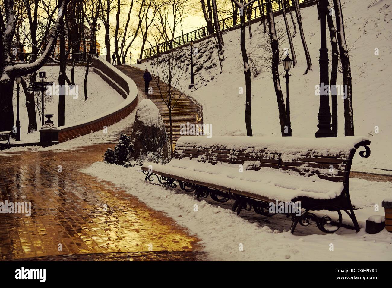 Bancs couverts de neige dans le parc, coucher de soleil doré Banque D'Images
