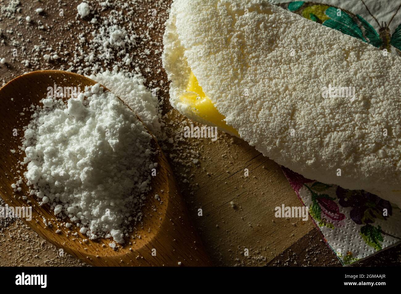 Tapioca, un plat typiquement brésilien, avec garniture de mozzarella sur une planche à découper et une cuillère en bois remplie de farine. Plat à base de farine. Banque D'Images