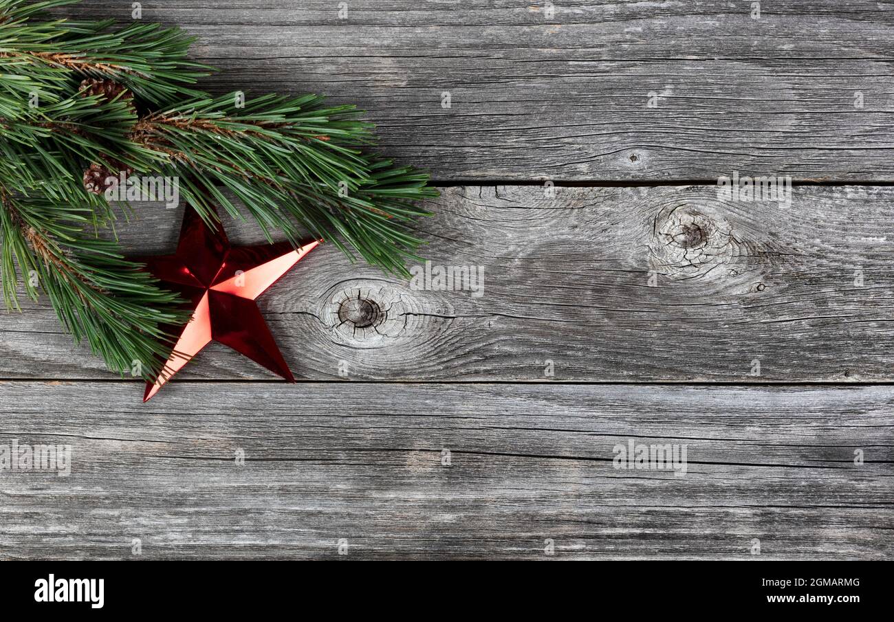 De véritables branches de sapin et un seul ornement d'étoile rouge sur fond rustique de planche en bois pour un joyeux Noël ou joyeux fête du nouvel an co Banque D'Images