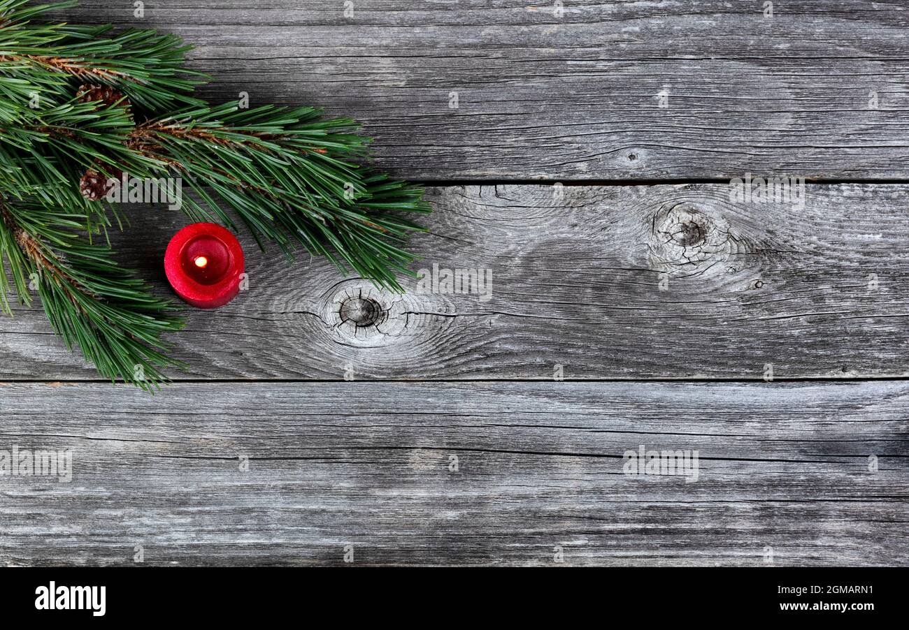 De véritables branches de sapin et un ornement de bougie rouge sur fond de bois rustique en planche pour un joyeux Noël ou une heureuse fête de nouvel an Banque D'Images