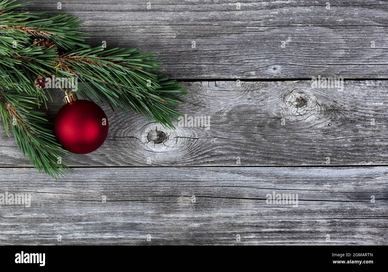 Véritable sapin branches et boule rouge ornement sur fond rustique en bois de planche pour un joyeux Noël ou joyeux Noël concept de fête du nouvel an Banque D'Images