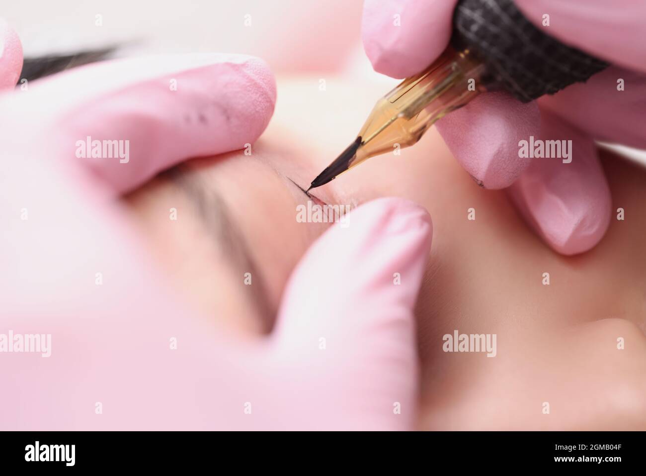 L'artiste maître de maquillage fait un maquillage permanent pour les paupières d'un client Banque D'Images