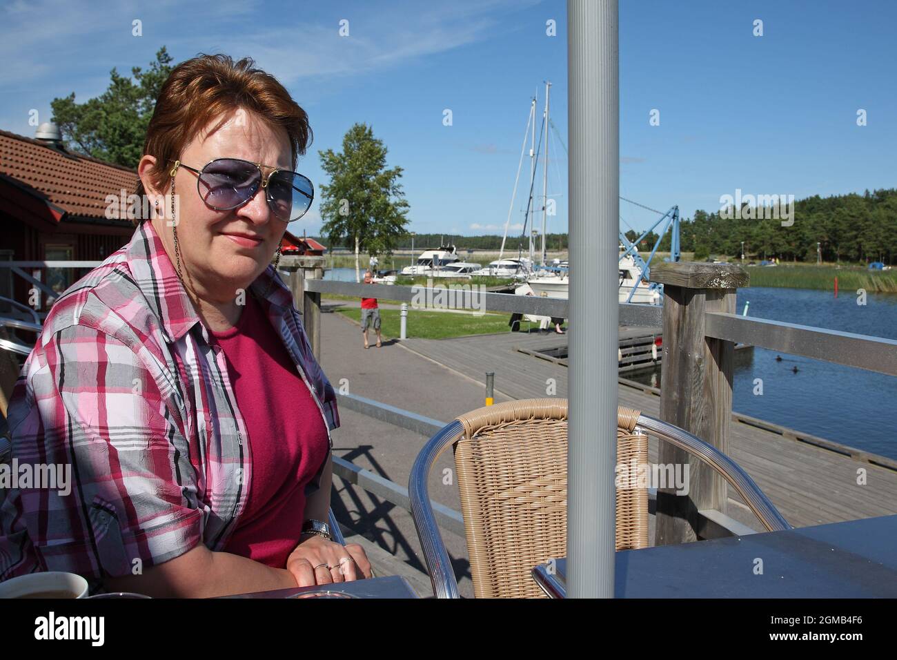 Une femme est assise sur la terrasse d'un café dans le port de Spiken et bénéficie de la vue sur le lac Vännern. Banque D'Images